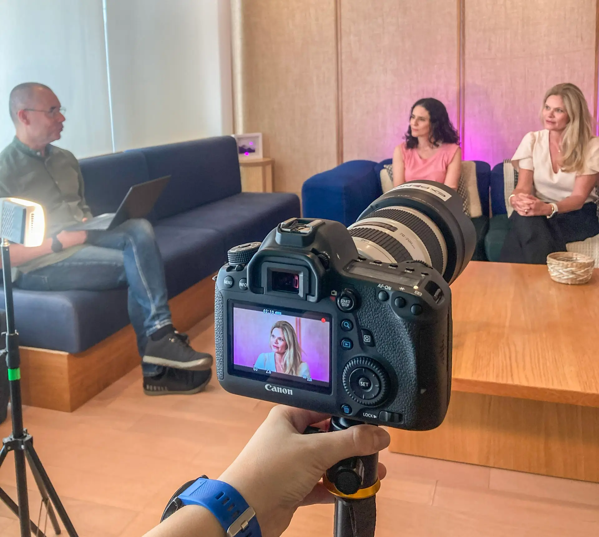 Camera gravando duas mulheres dando entrevista para um homem brando.